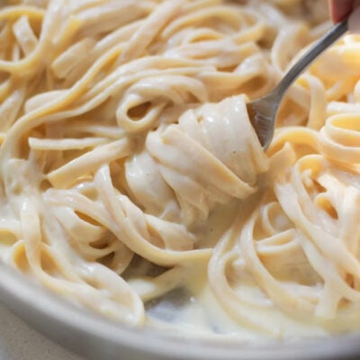 Fettuccine alfredo being twirled with a fork.